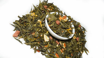 A pile of loose-leaf herbal tea with dried green leaves, orange flower petals, and small pinkish-brown pieces, with a small white scoop resting in the center, on a plain white background.


